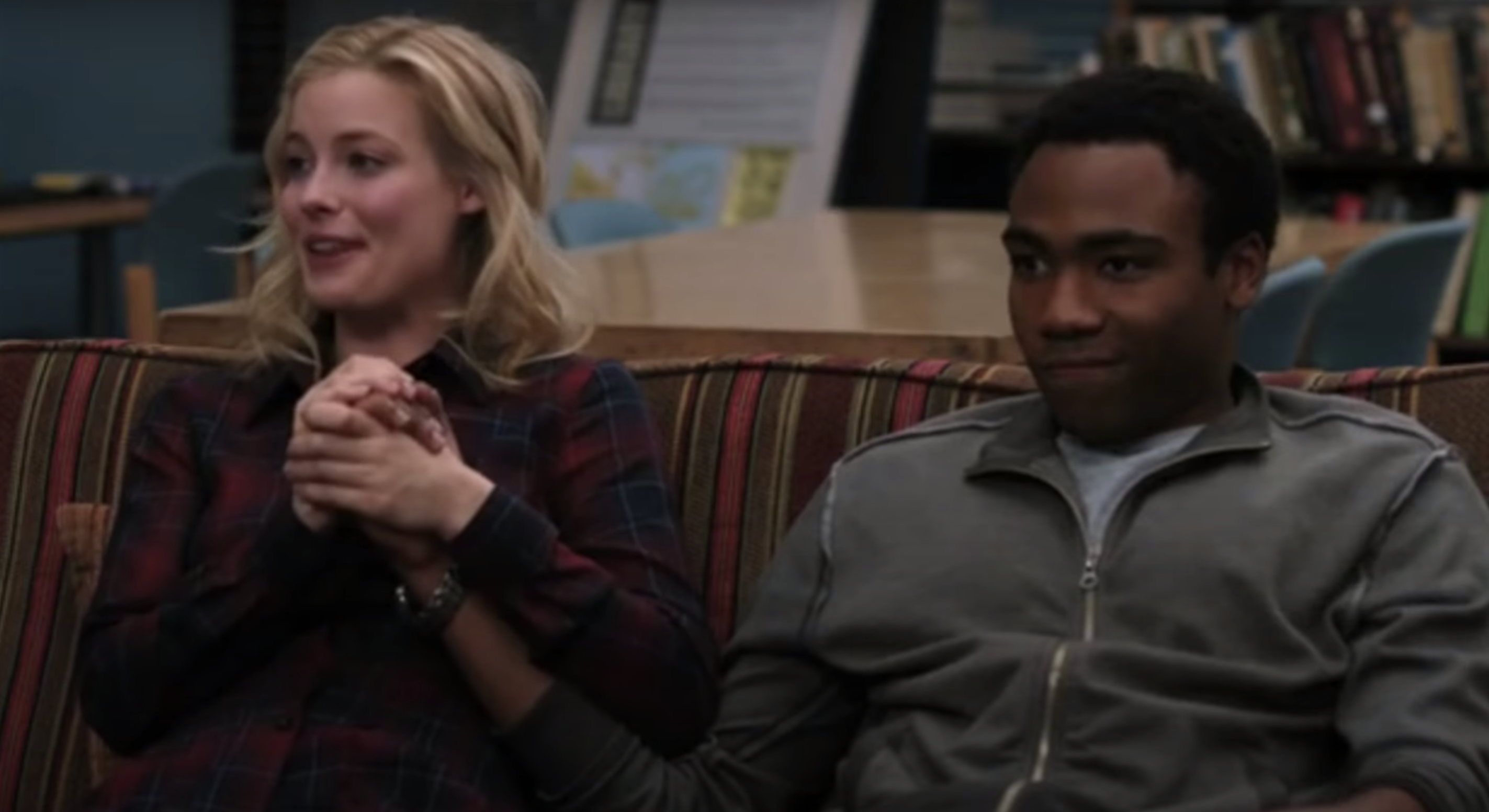 Britta holding Troy&#x27;s hand as they sit on a couch