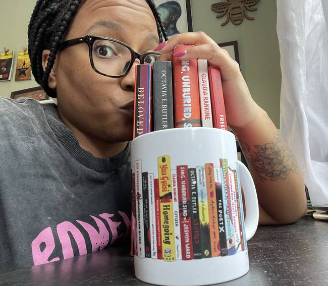 buzzfeed writer Taylor kissing a stack of books that mirror the books featured on the spines and vines mug