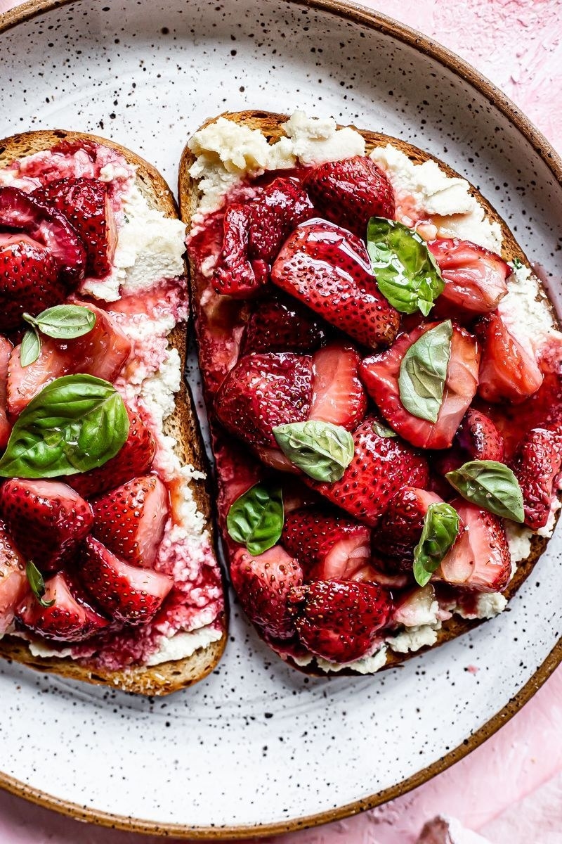 Two slices of toast topped with ricotta cheese and strawberries