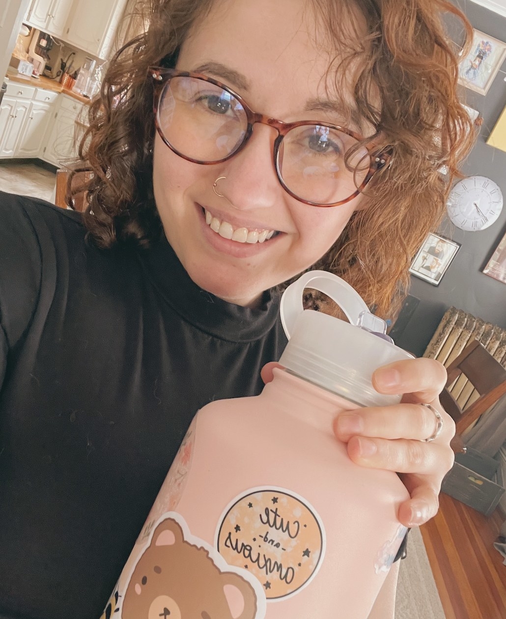 A person smiling while holding a pink water bottle