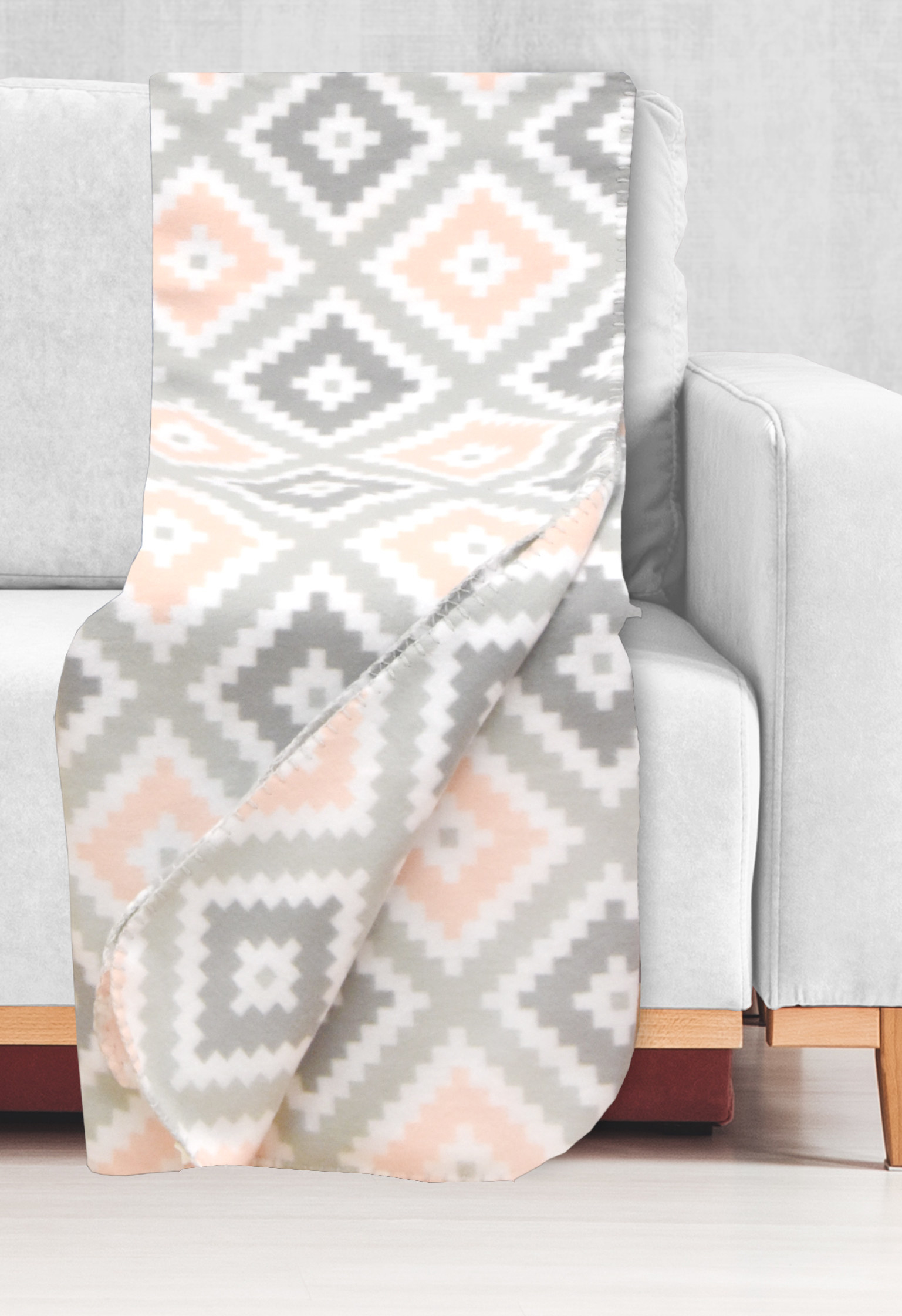 A pink and grey patterned blanket on a white couch