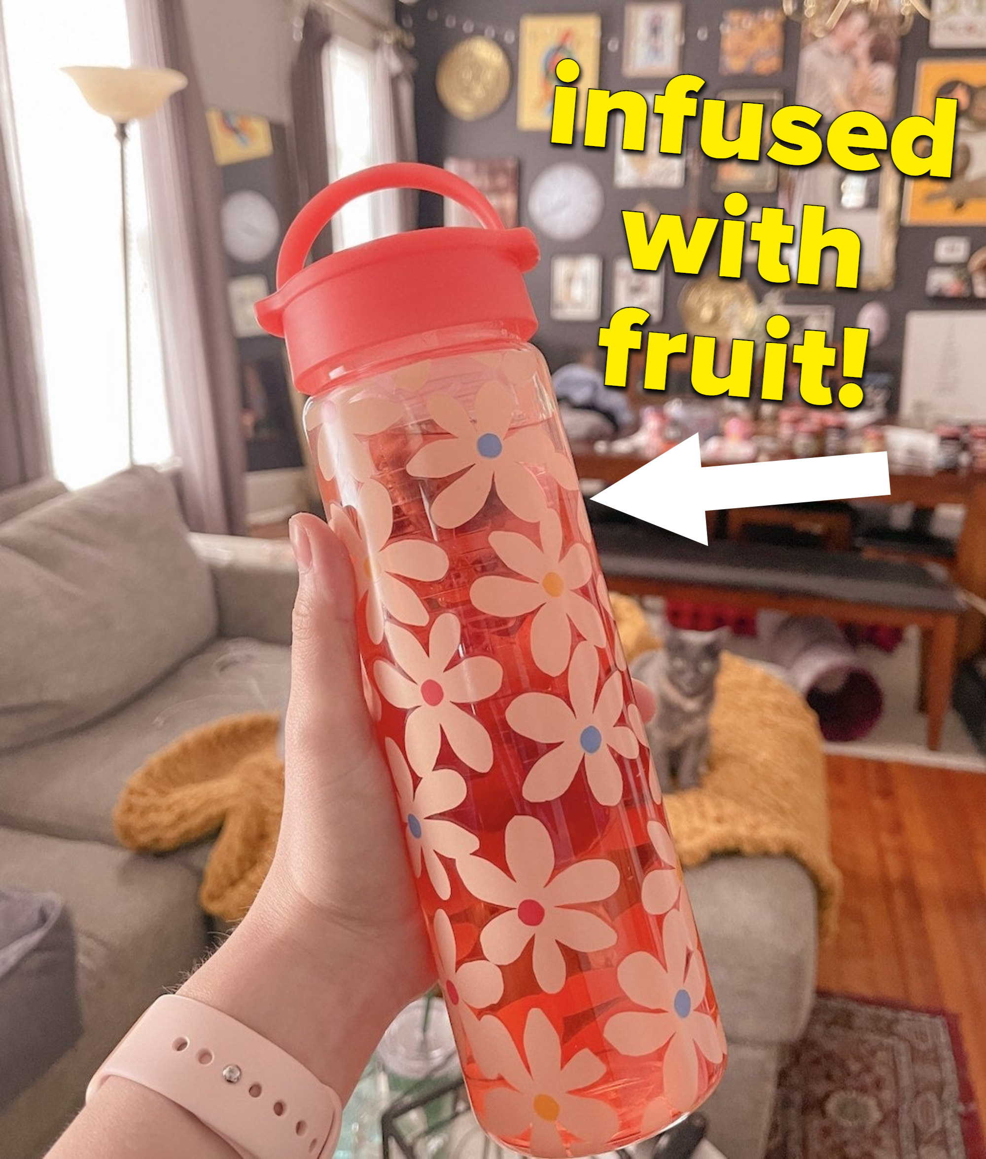 A person holding a glass bottle with fruit inside it