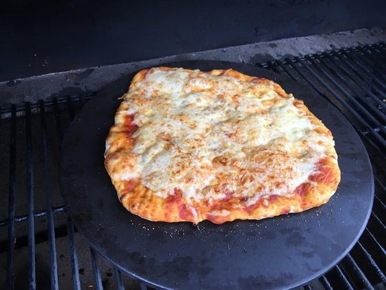 reviewer photo showing a pizza on their grill on the pizza stone