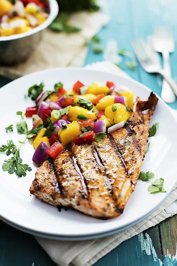 A piece of grilled salmon with mango salsa.