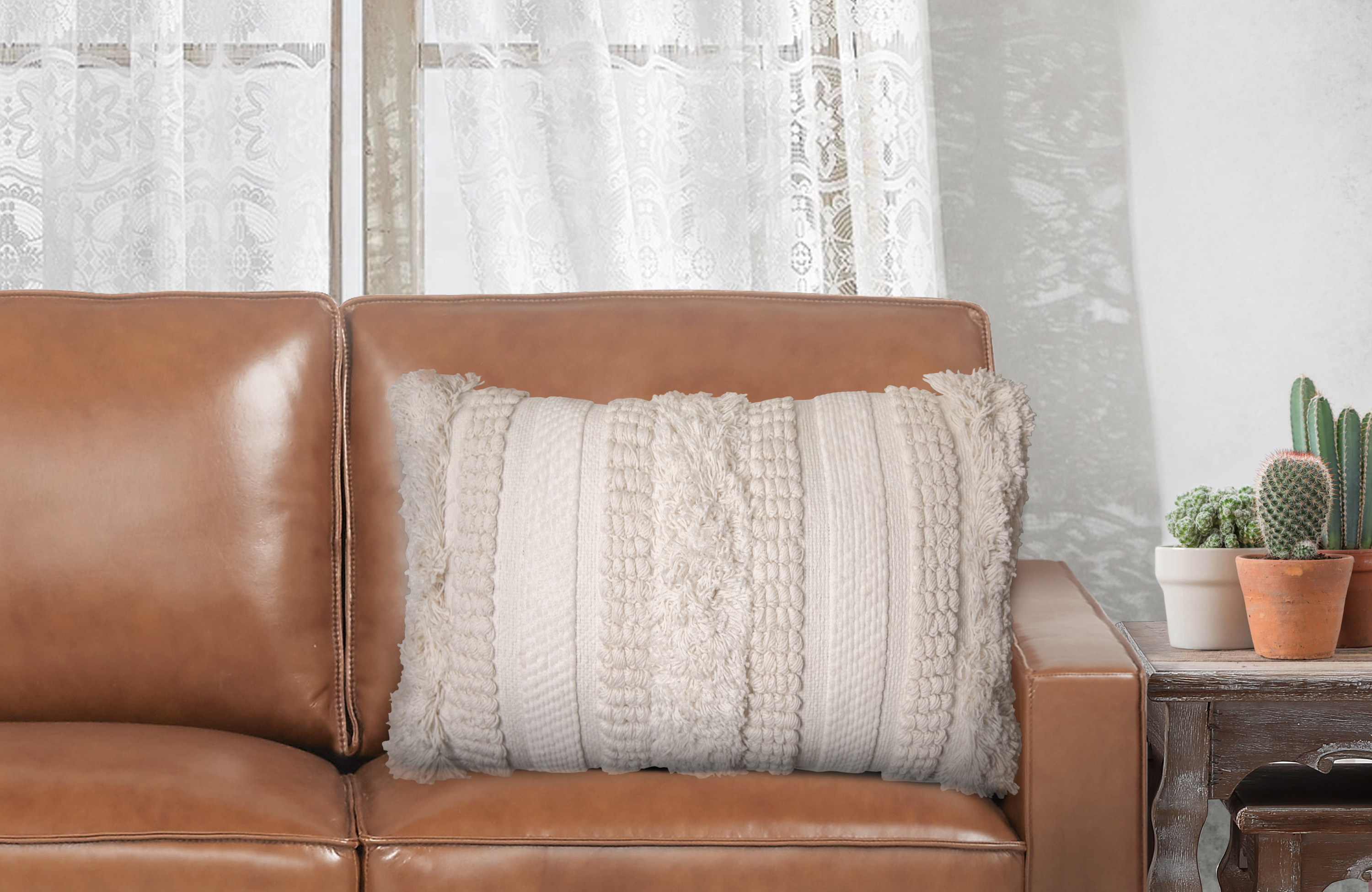 A white boho textured pillow on a brown couch