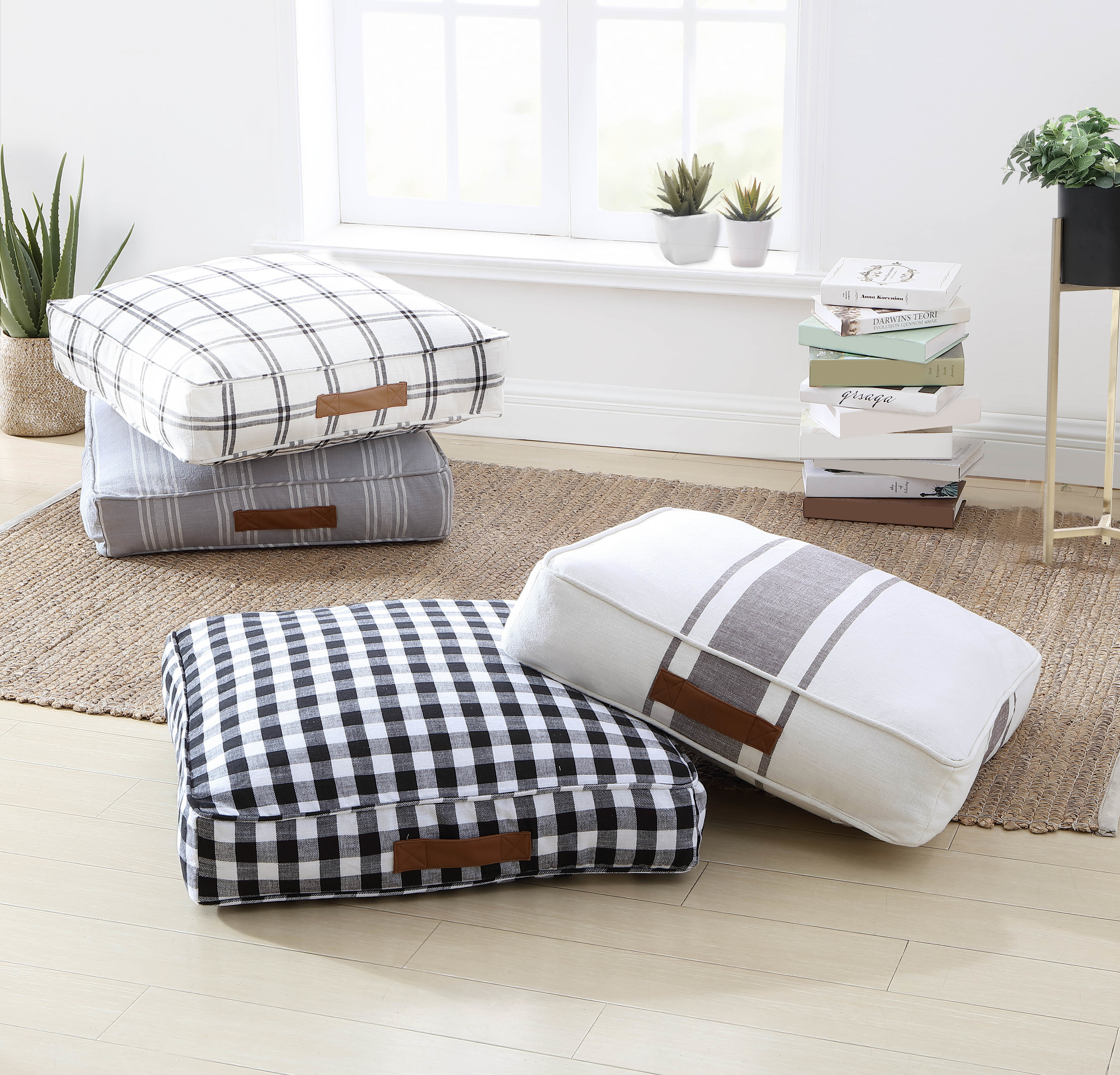 gray, black, and white floor cushions in stripe and check prints on a floor, with brown handles