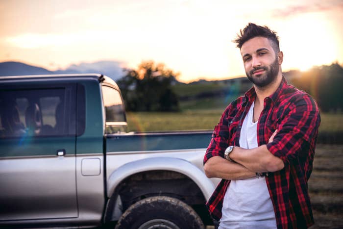 Man standing next to a truck while wearing a plaid shirt