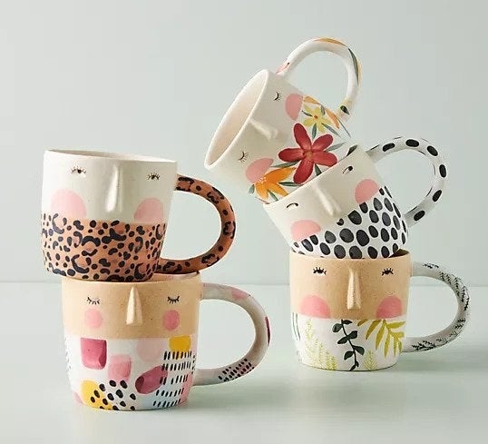 Several mugs that look like faces with outfits on