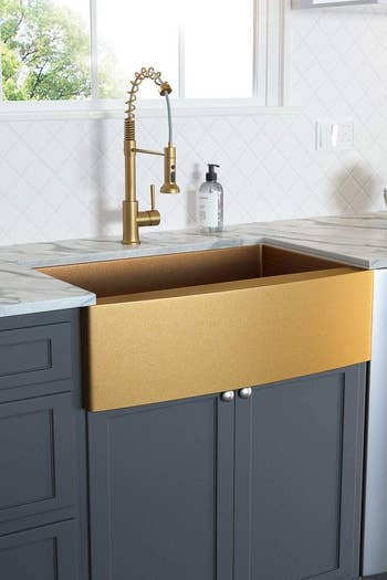 A gold farmhouse sink with matching faucet 