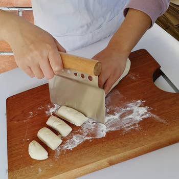 person using bench scraper to divide pieces of dough