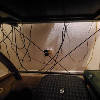 a reviewer photo of a mess of cords under a desk 