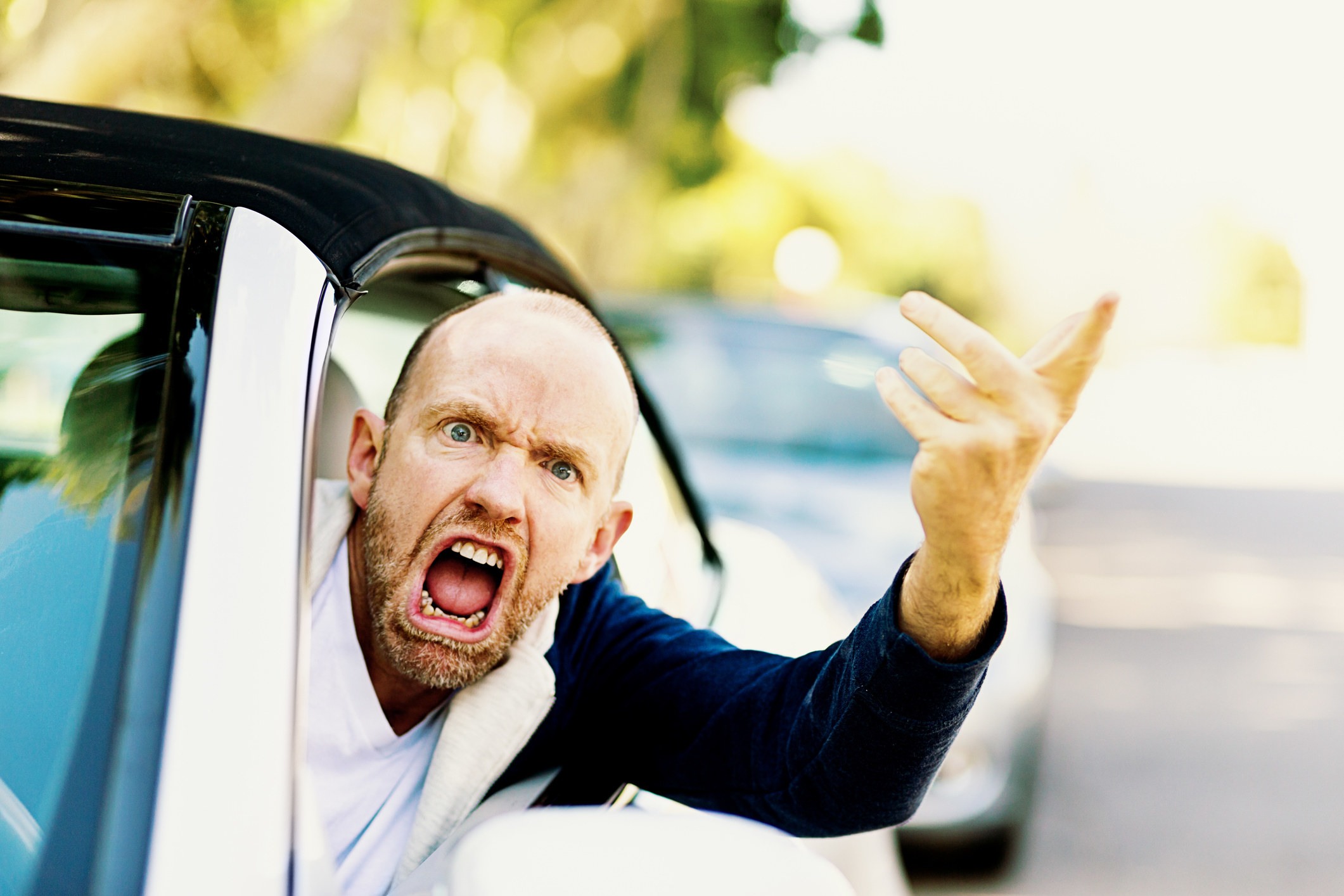 Man leaning out the driver&#x27;s seat of a car shouting and pointing