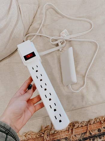 a reviewer holding the outlet cover with a power strip attached 