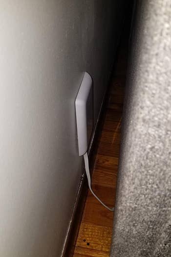 a reviewer's slim outlet cover with a piece of furniture up against the wall 