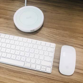 a reviewer photo of a white keyboard and mouse next to a white circular mug warmer 