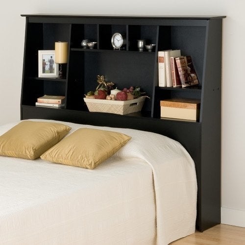 The headboard with pictures, decor, books, and miscellaneous items