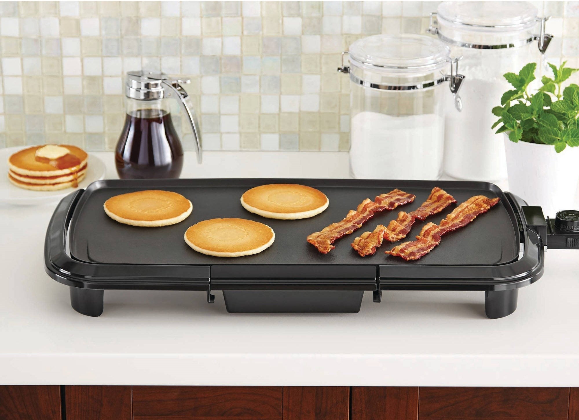 griddle on a countertop with pancakes and bacon on top