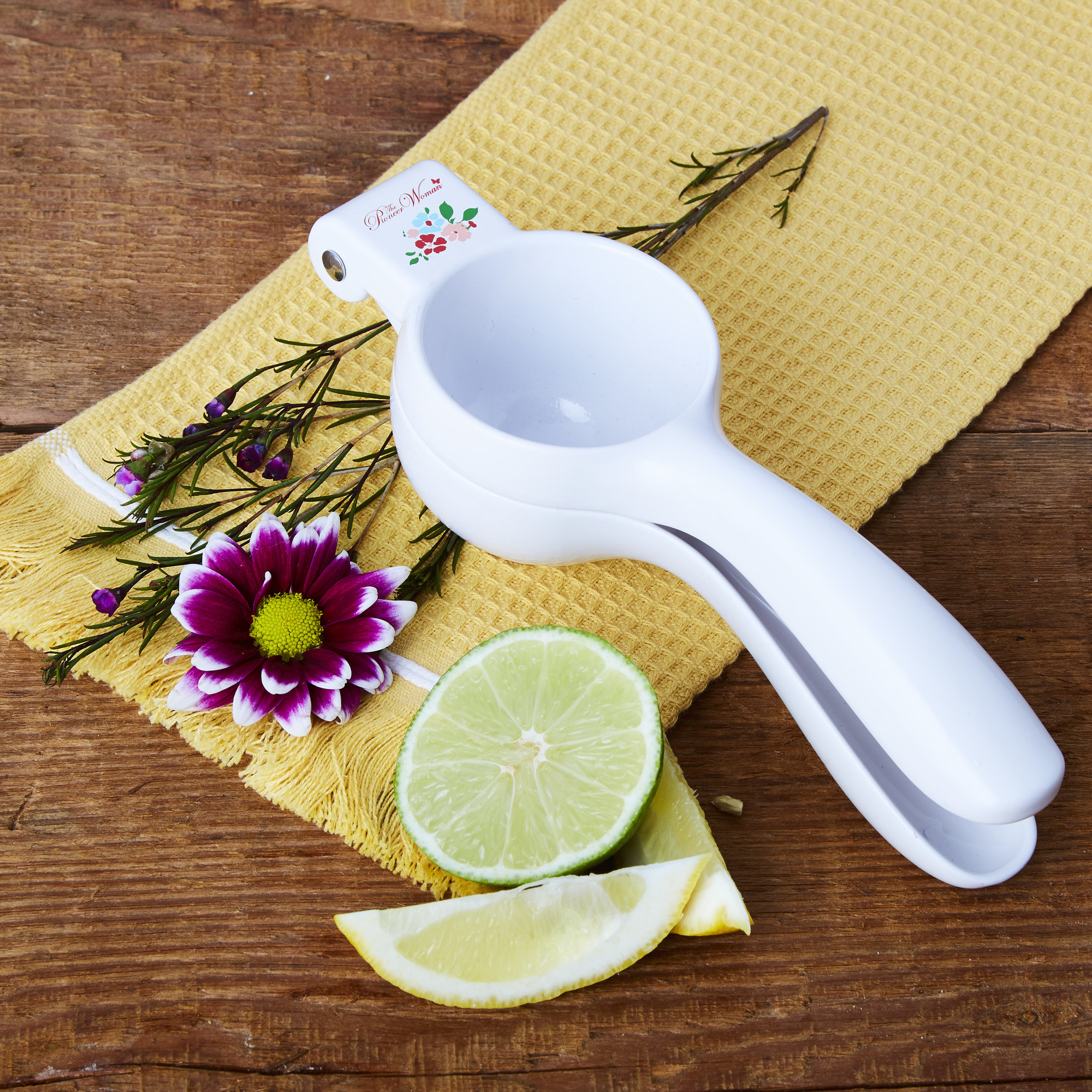 white handheld citrus juicer on a table next to a cut up lime