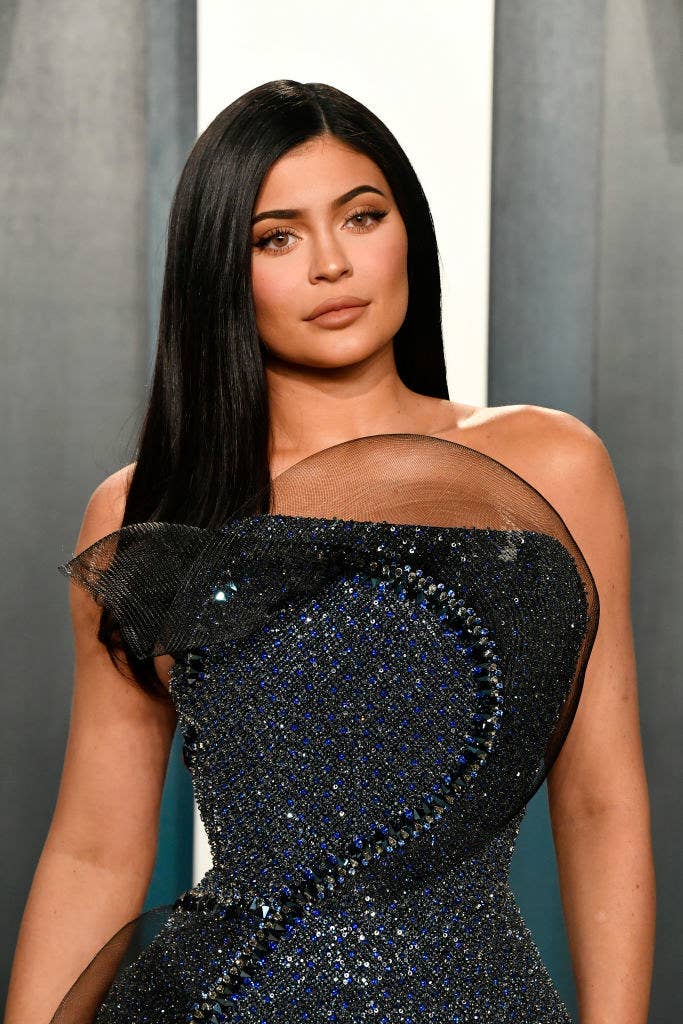 Kylie posing on a red carpet in a strapless sequined gown