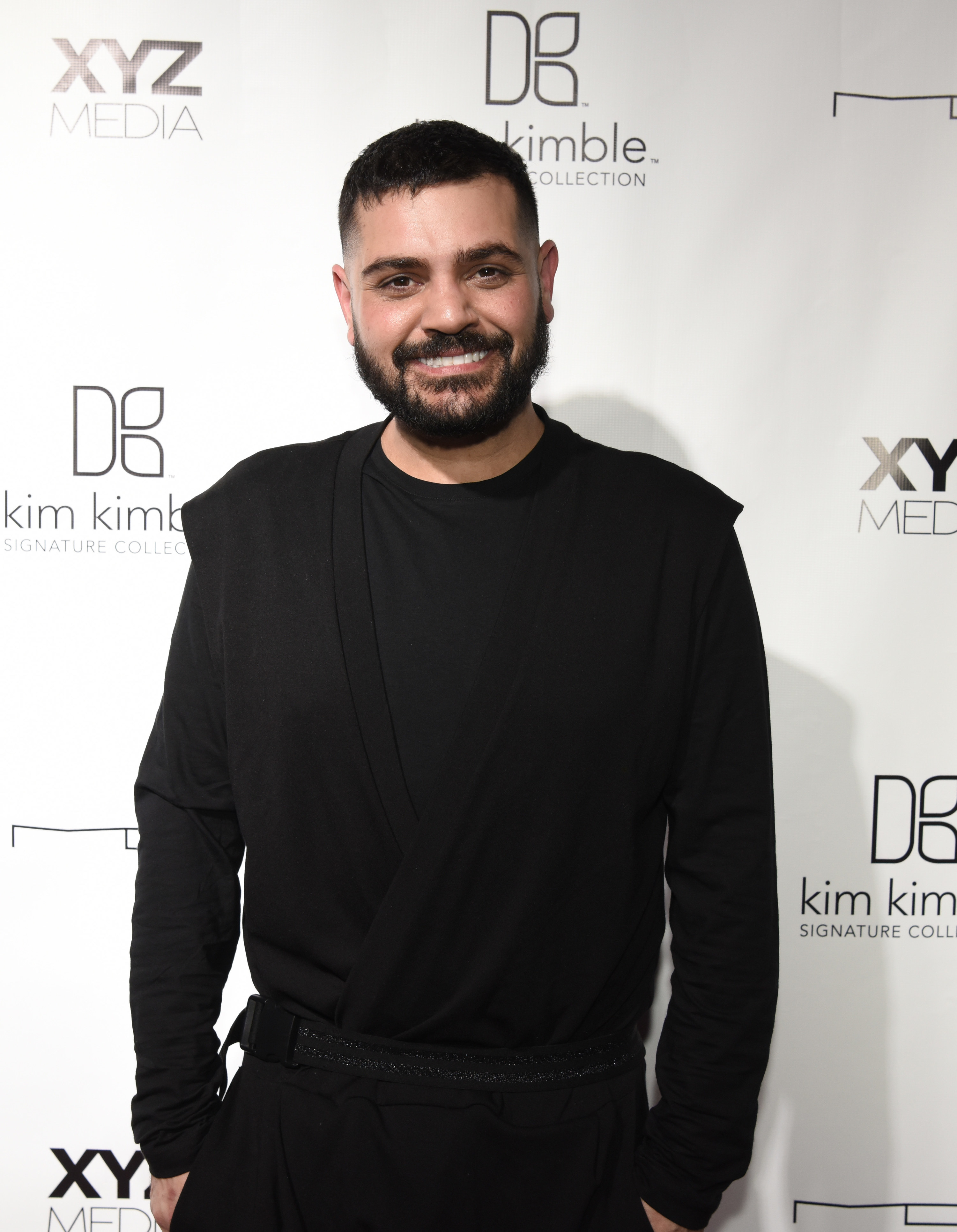 Michael Costello, with hands in pocket, stands on the red carpet