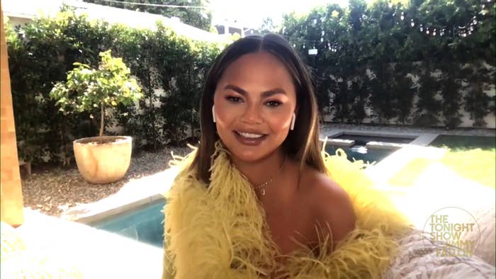 Chrissy Teigen smiling in front of a pool