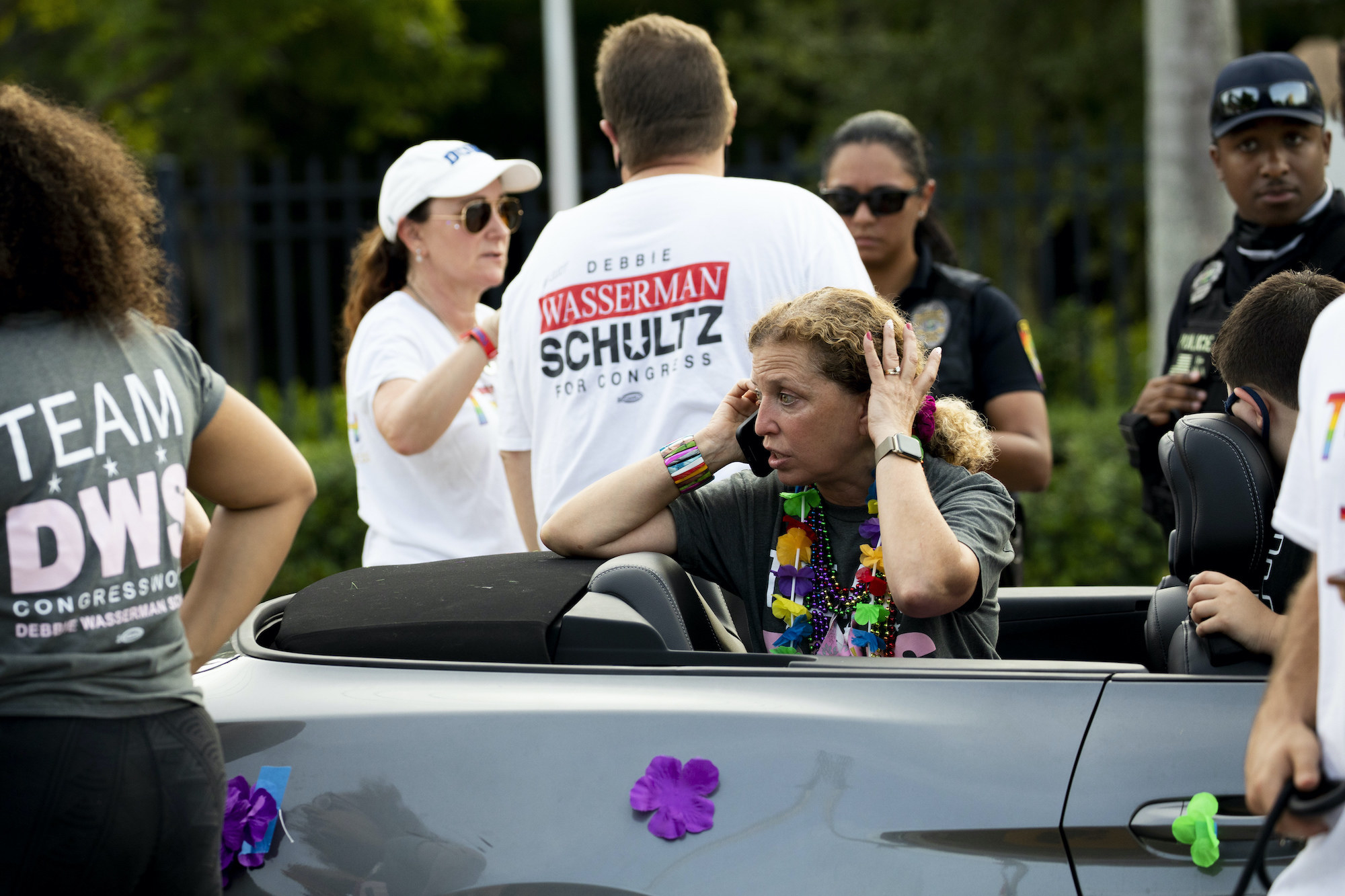 Debbie Wasserman Schultz is on the phone in the back of a convertible looking panicked