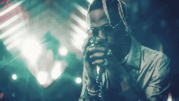Travis Scott grabs a microphone on a stand and raps