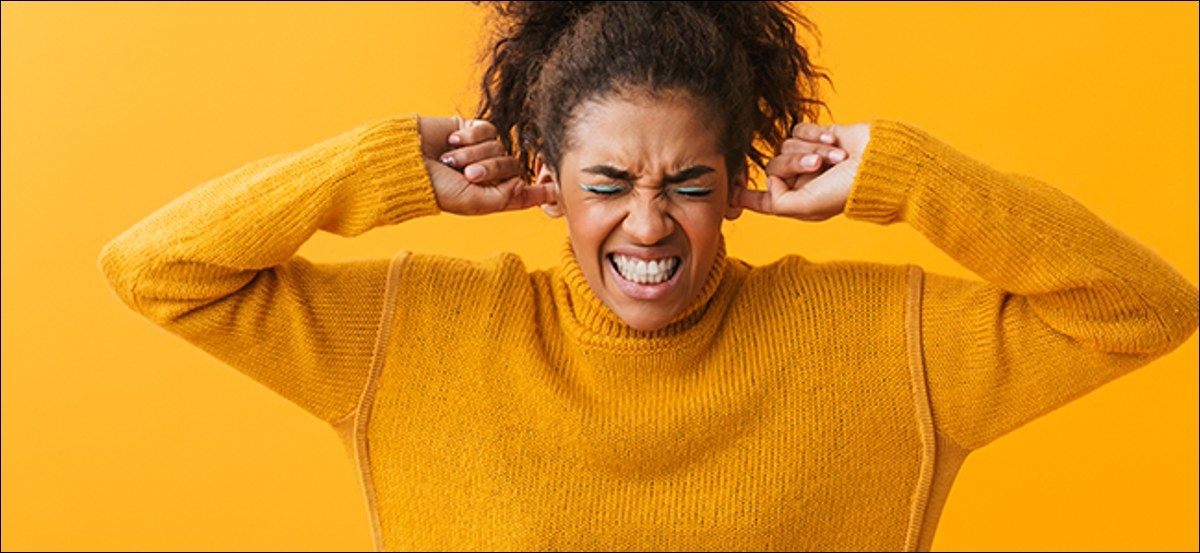 Woman plugging her ears while grimacing as if something is too loud. 