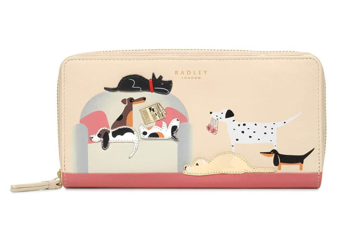 a zip around wallet with various dogs on it lying on a couch