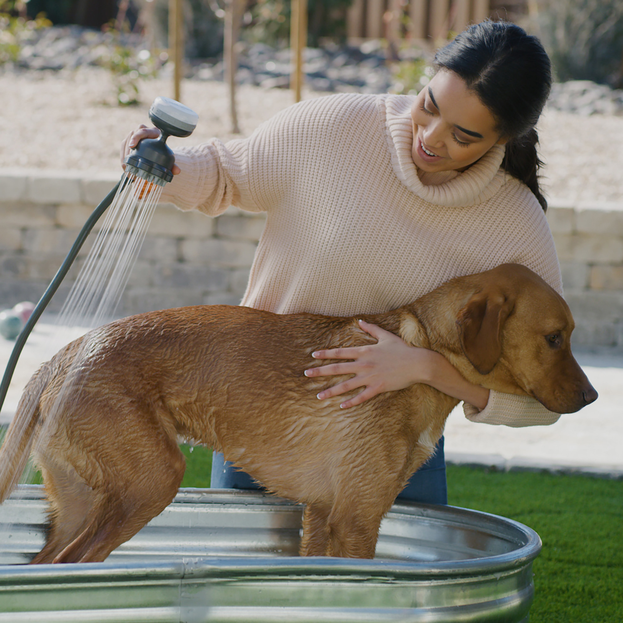 model using the washer on her dog in an outside tub