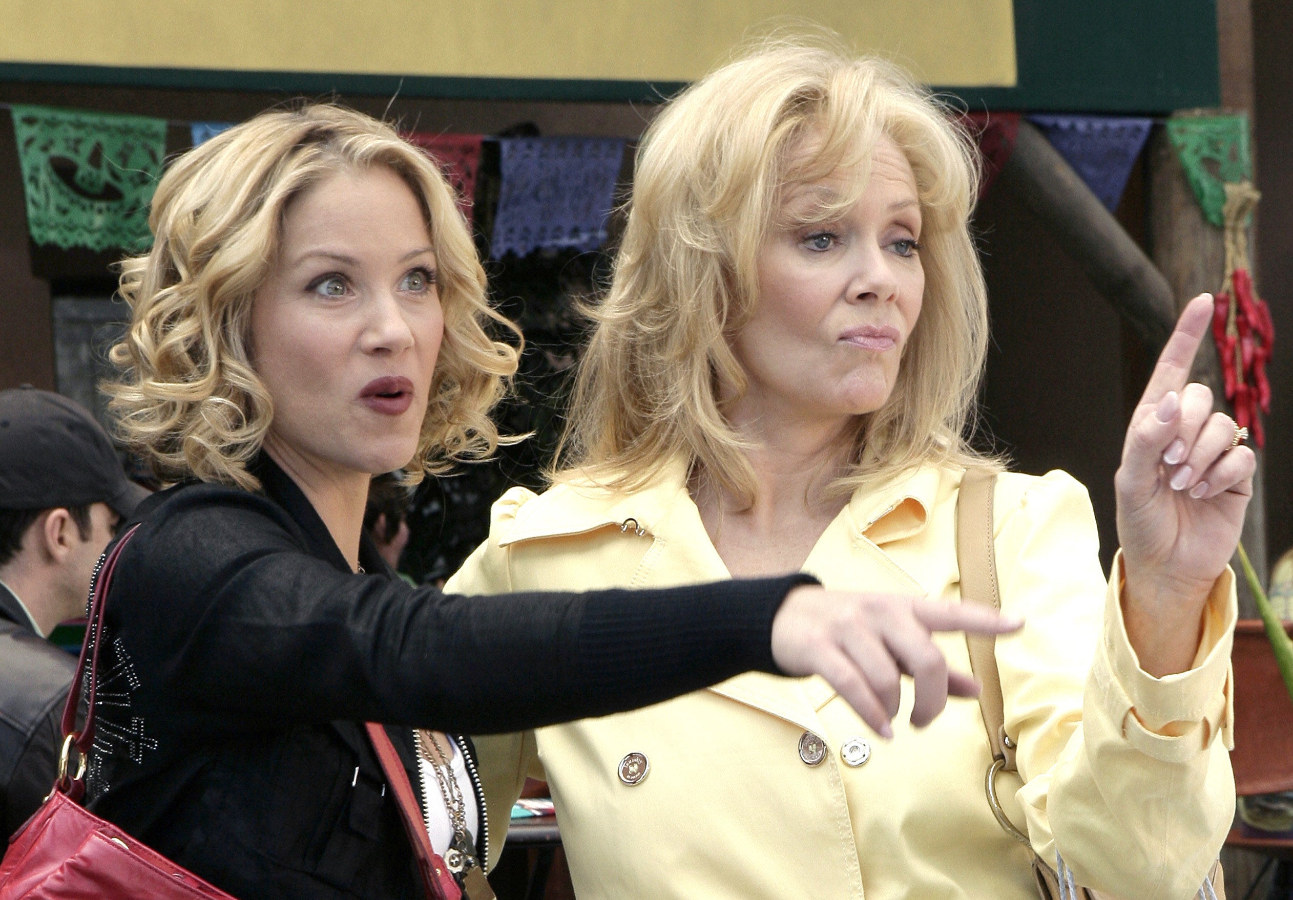 Two blonde women with their fingers raised talking to someone offscreen