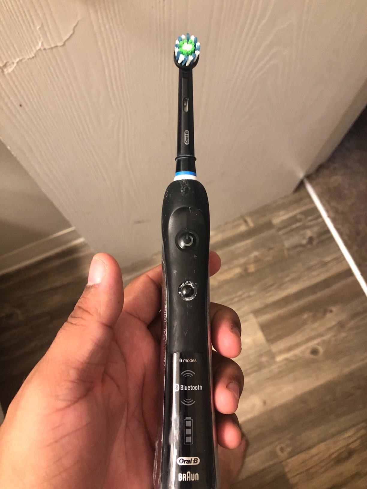 Reviewer holding the black toothbrush