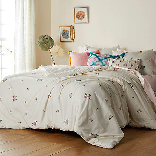 Neutral-toned floral comforter set on a bed.