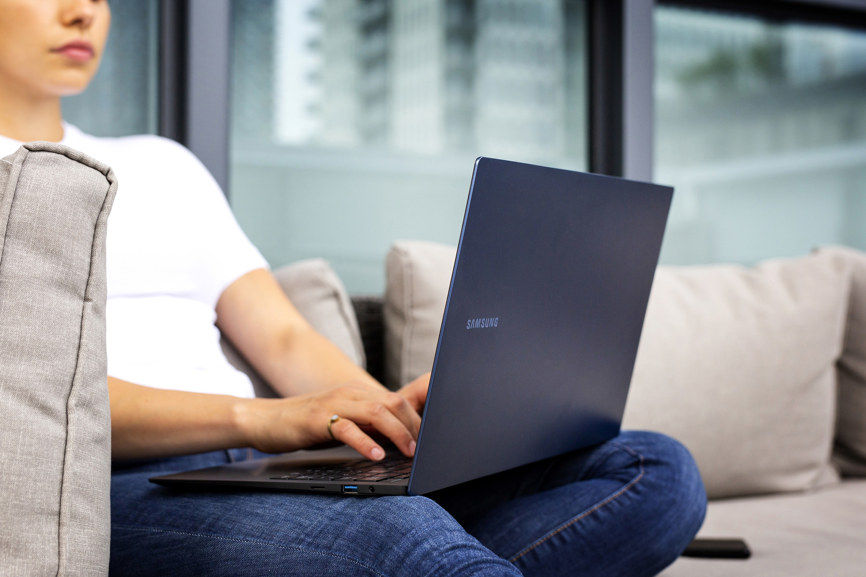 A person sitting on an outdoor couch with their laptop