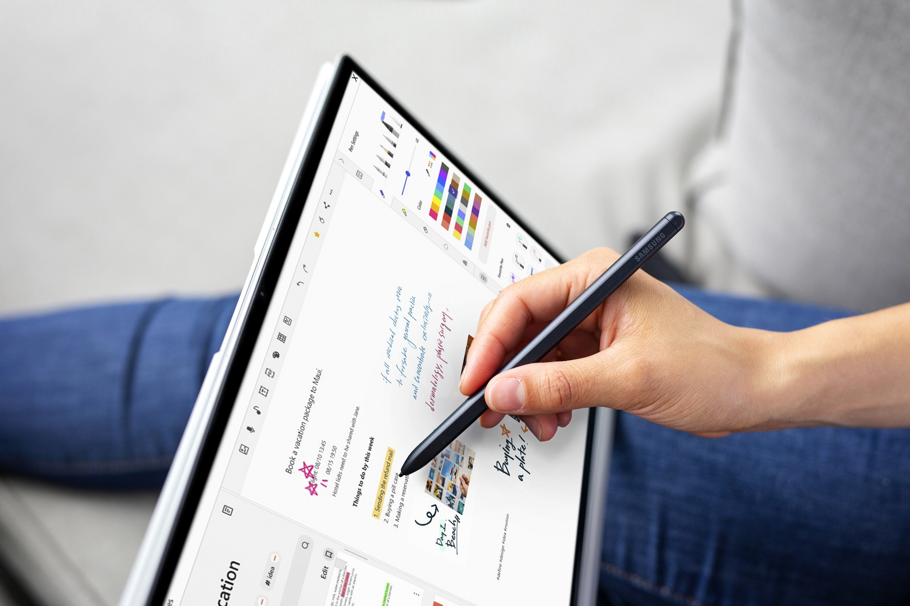 A person holding a stylus pen while working on a tablet