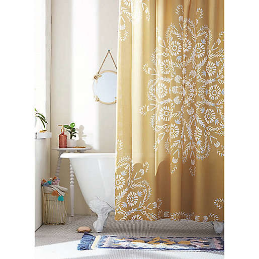 A bathroom and bathtub with an ochre floral shower curtain.