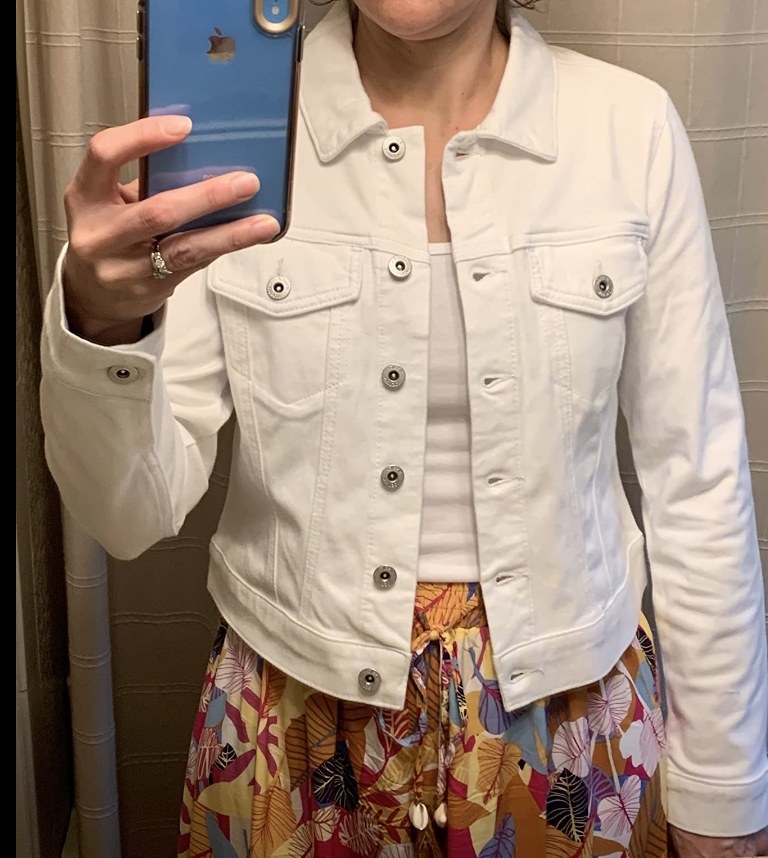 A reviewer talking a mirror selfie wearing a white denim jacket