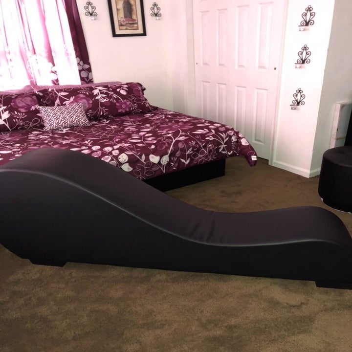 Black curved chaise in bedroom from side angle