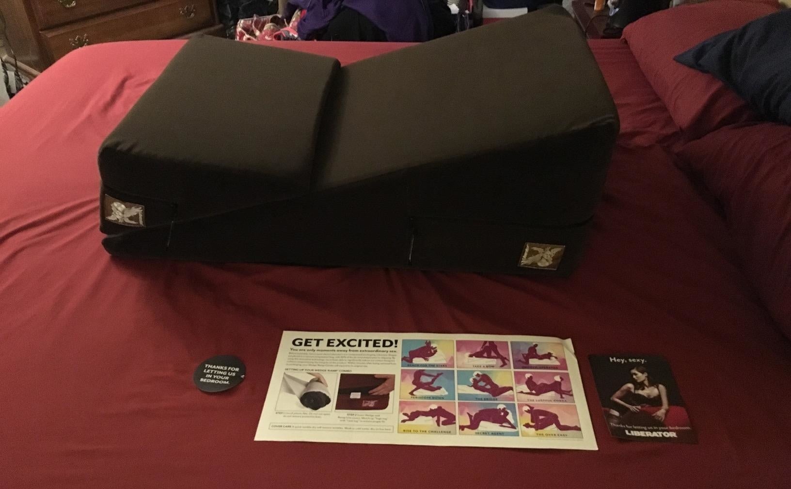 Black ramp and wedge pillow on bed next to booklet of positions