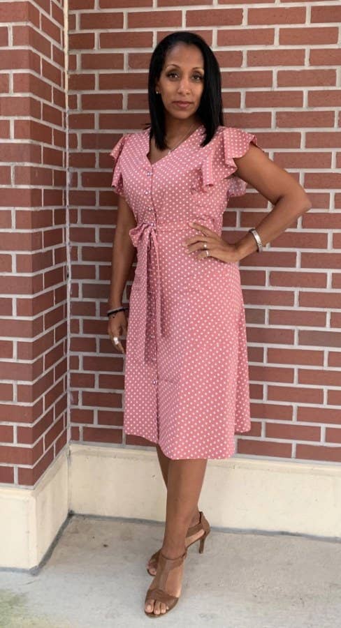 A reviewer wearing a pink/white polka dotted swing dress with pockets outside