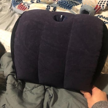 Model holding blue inflatable half-moon pillow from front