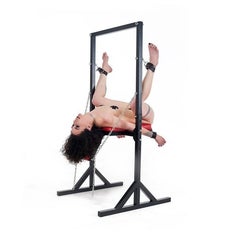 Woman in standing bondage chair with legs cuffed and head tilted back from side angle