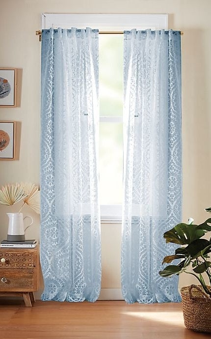 Light blue patterned curtain hanging on a windowsill.