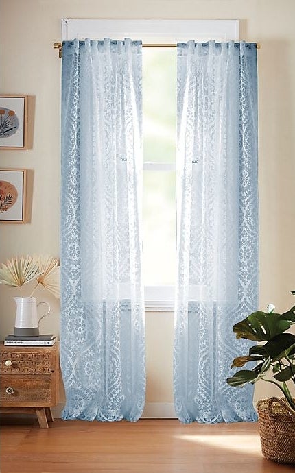 Light blue patterned curtain hanging on a windowsill.