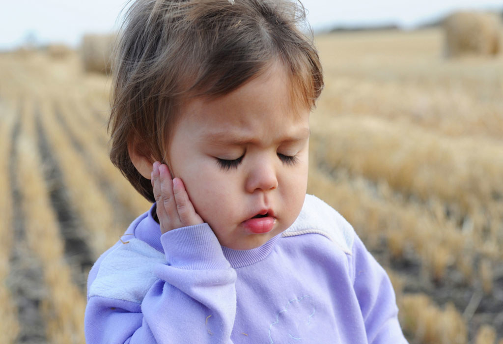 Child holding ear in pain and looking sad. 