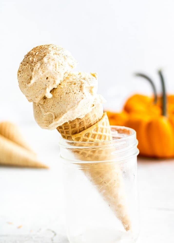 Two scoops of pumpkin ice cream on a cone in a clear mason jar. 