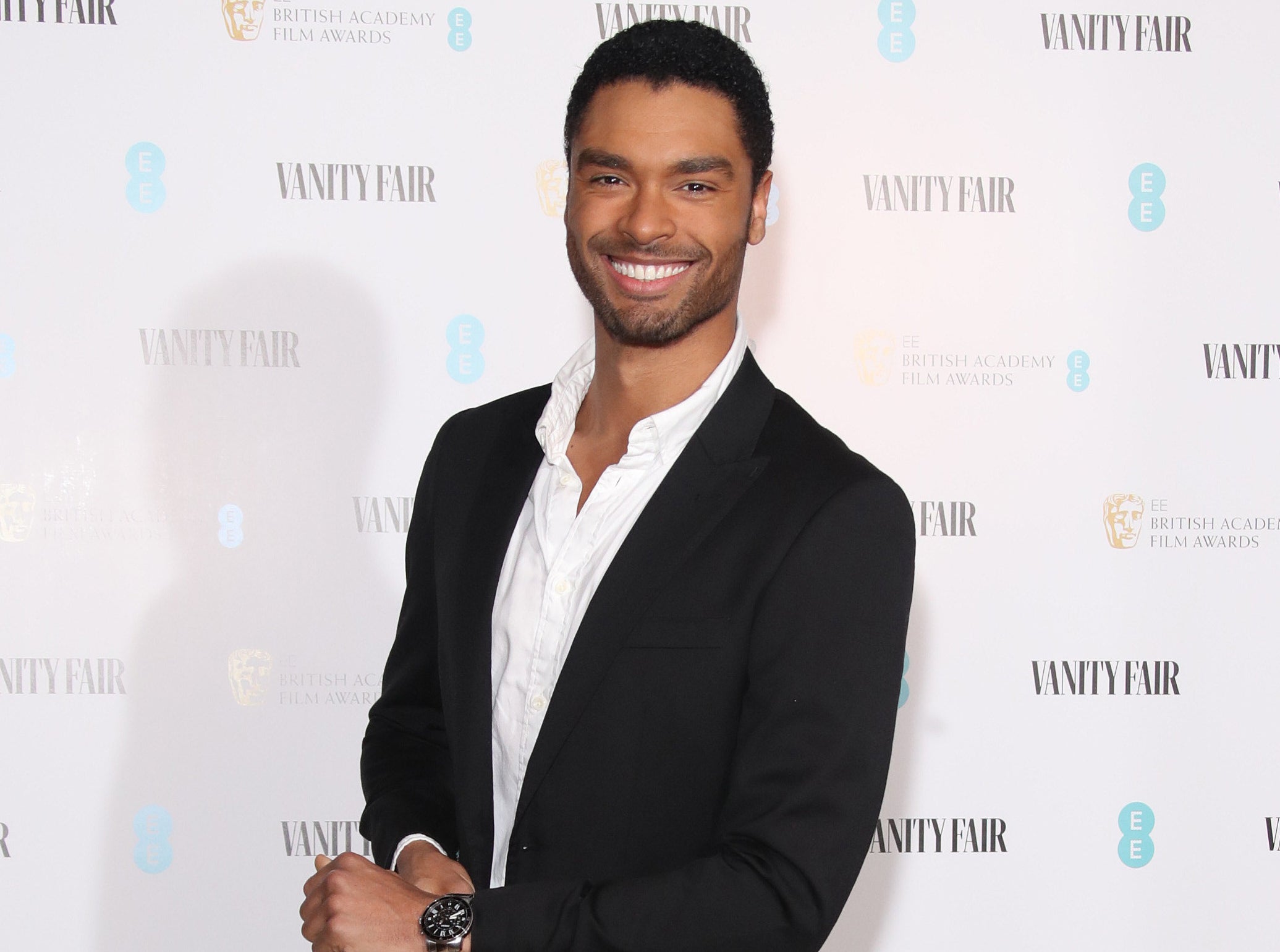 Regé-Jean smiles while standing on a red carpet