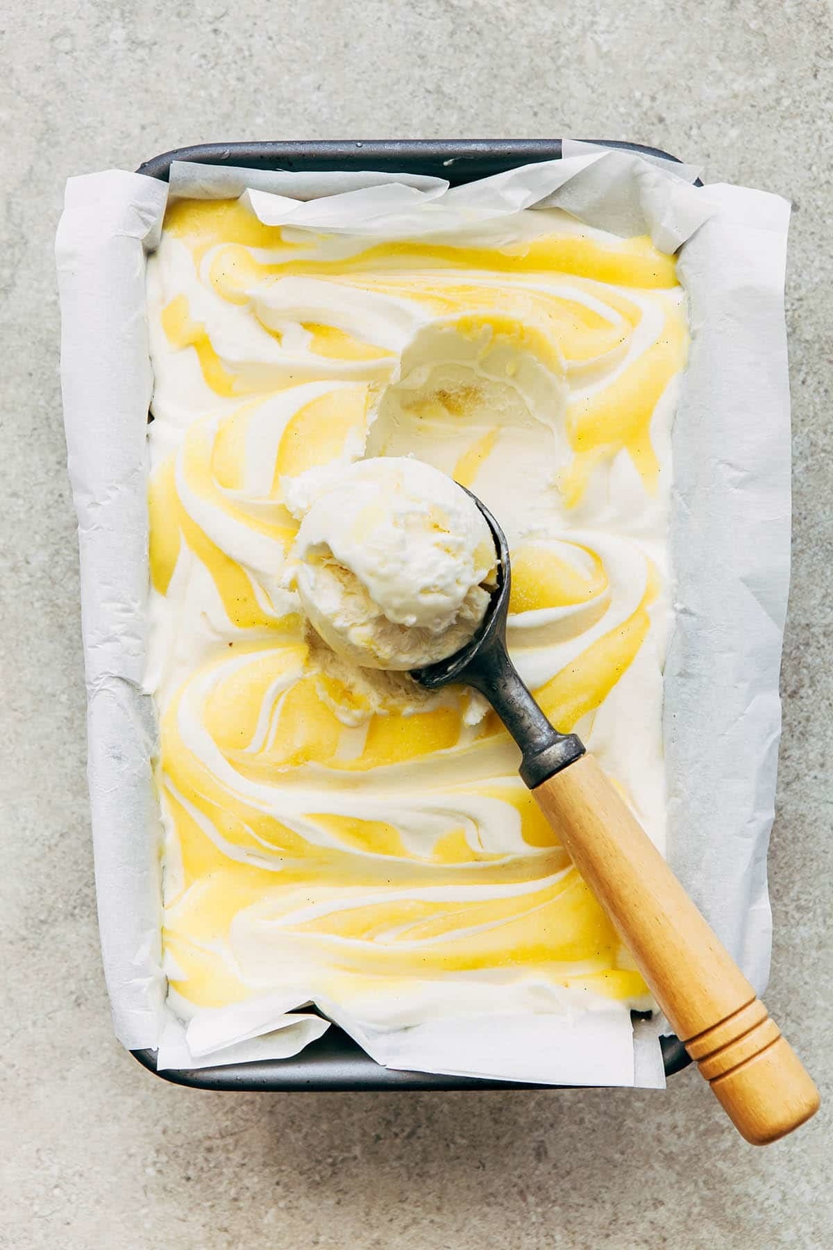 Ice cream swirled with lemon curd being scooped.