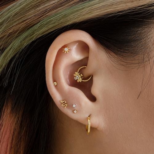 A model wearing the gold bee-clicker earring in a daith piercing
