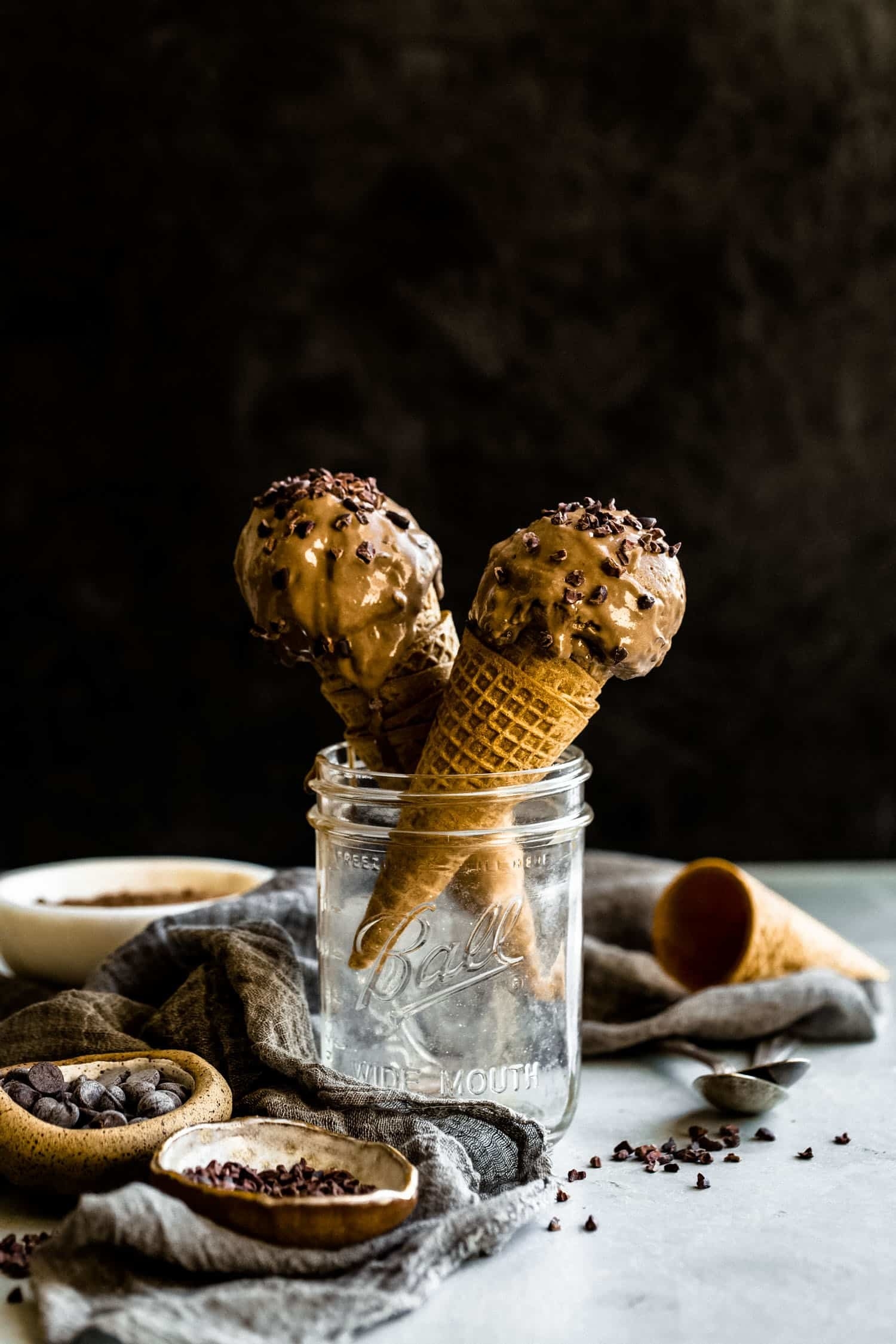 Scoops of chocolate ice cream in cones in a glass mason jar. 